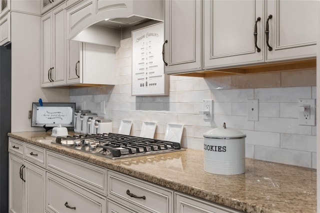 kitchen featuring stainless steel gas cooktop, light stone countertops, decorative backsplash, and white cabinetry