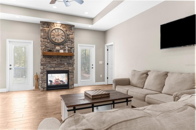 living room with a fireplace, ceiling fan, and light hardwood / wood-style floors