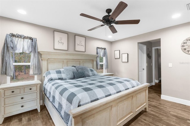 bedroom featuring ceiling fan, dark wood-type flooring, and multiple windows