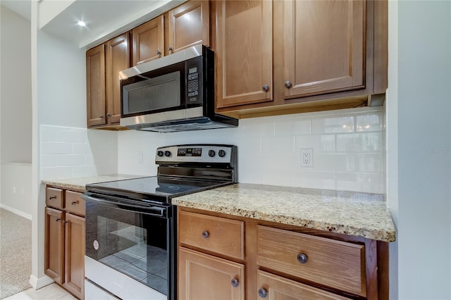 kitchen with light stone counters, light colored carpet, backsplash, and appliances with stainless steel finishes