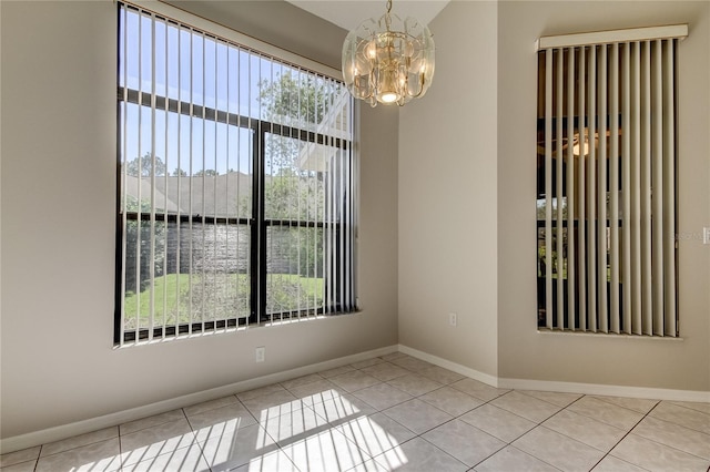 tiled empty room with a notable chandelier, a water view, and plenty of natural light