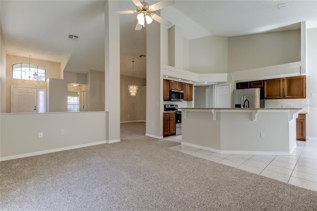 kitchen with an island with sink, stainless steel appliances, light carpet, and a breakfast bar area