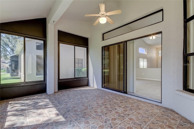 unfurnished sunroom featuring a healthy amount of sunlight, ceiling fan, and lofted ceiling