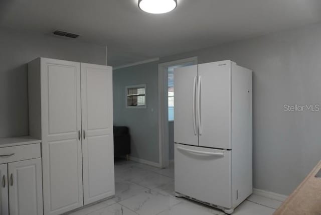 kitchen featuring white cabinets and white fridge