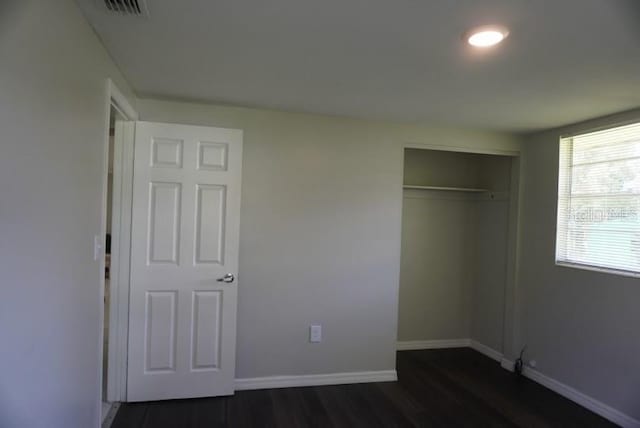 unfurnished bedroom featuring a closet and dark hardwood / wood-style flooring