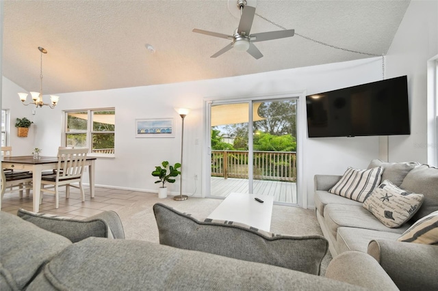 tiled living room featuring a textured ceiling, high vaulted ceiling, and ceiling fan with notable chandelier