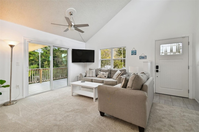 living room featuring ceiling fan, high vaulted ceiling, light colored carpet, and a textured ceiling