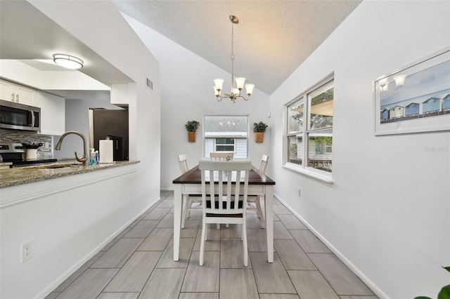 dining space featuring a chandelier, a textured ceiling, vaulted ceiling, and sink