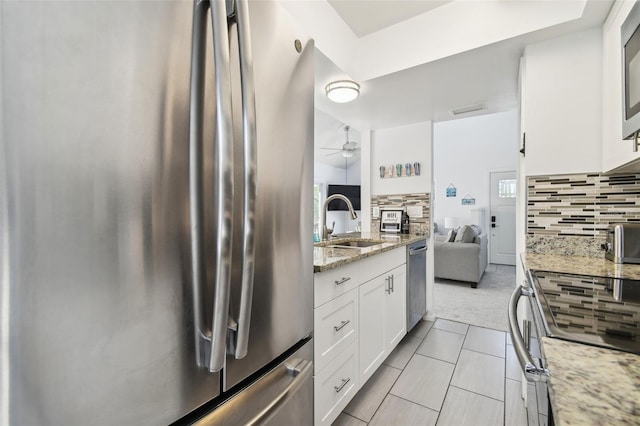 kitchen with backsplash, white cabinets, sink, light stone counters, and stainless steel appliances