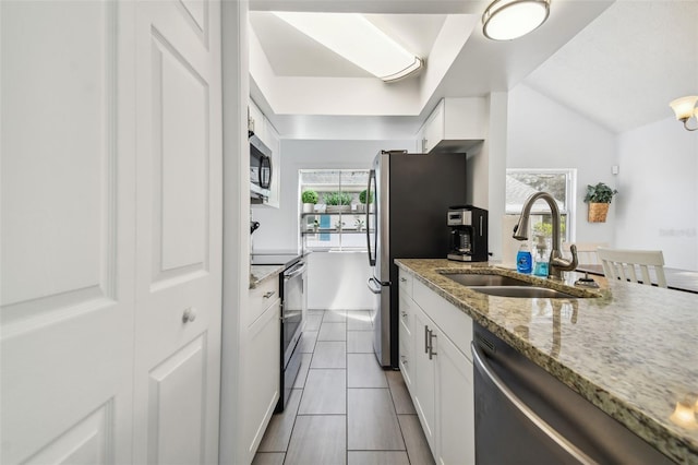 kitchen with white cabinetry, sink, light stone countertops, lofted ceiling, and appliances with stainless steel finishes