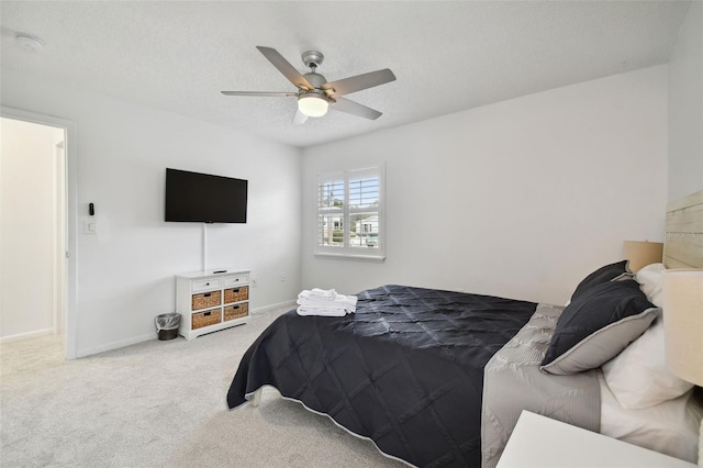 carpeted bedroom featuring ceiling fan and a textured ceiling