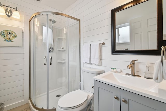 bathroom with walk in shower, wooden walls, vanity, and toilet