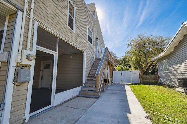 view of property exterior with a patio area, a sunroom, a yard, and central AC unit