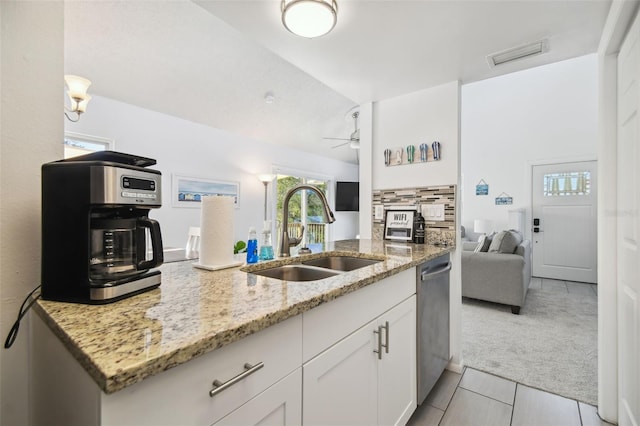 kitchen featuring light stone countertops, dishwasher, sink, light tile patterned flooring, and white cabinets