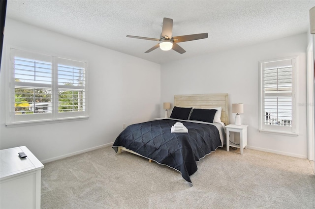 carpeted bedroom featuring ceiling fan and a textured ceiling