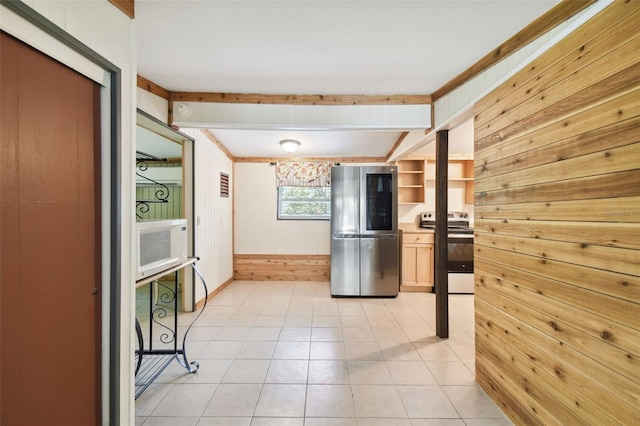 kitchen with stainless steel appliances, light brown cabinetry, wood walls, and light tile patterned floors