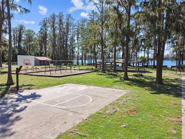 view of basketball court featuring a water view and a yard