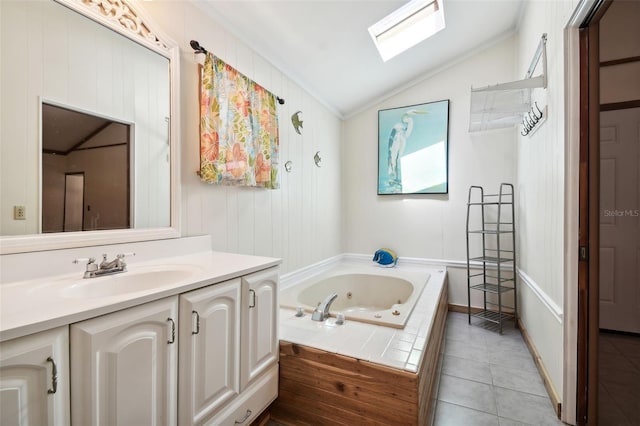 bathroom with vanity, vaulted ceiling with skylight, tile patterned flooring, and tiled bath