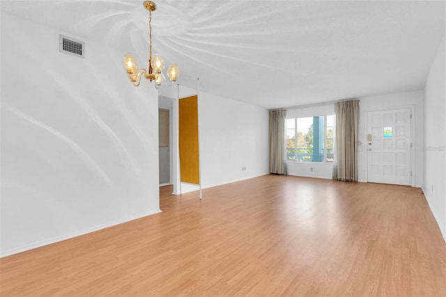 unfurnished living room with a notable chandelier and light wood-type flooring