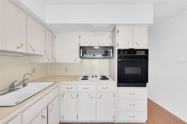 kitchen with white electric cooktop, white cabinetry, black oven, light wood-type flooring, and sink