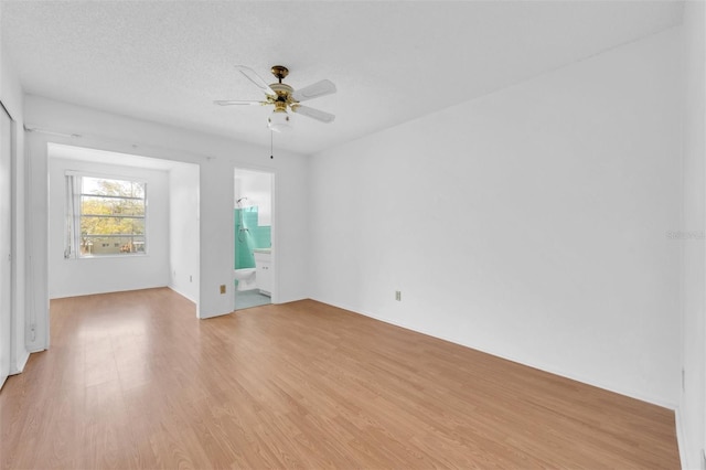 empty room featuring light hardwood / wood-style flooring, a textured ceiling, and ceiling fan