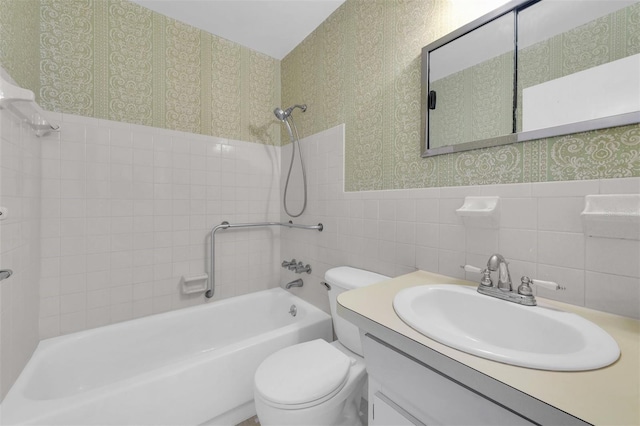 full bathroom with toilet, tiled shower / bath combo, vanity, and tile walls