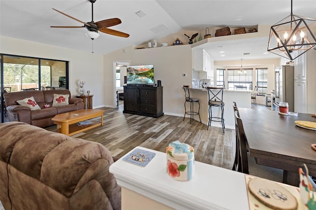 living room featuring light wood-type flooring, vaulted ceiling, and a healthy amount of sunlight