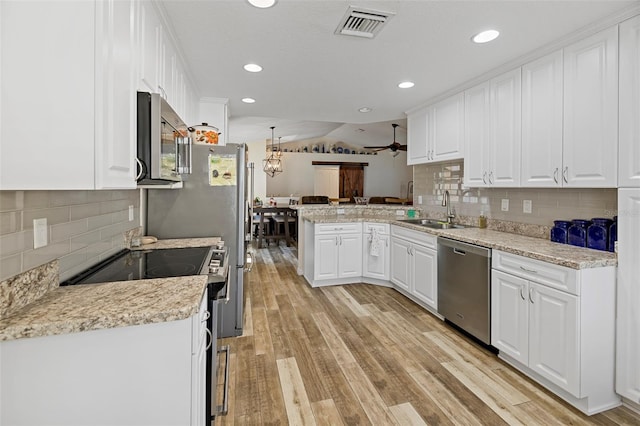 kitchen featuring light hardwood / wood-style floors, sink, kitchen peninsula, appliances with stainless steel finishes, and white cabinetry