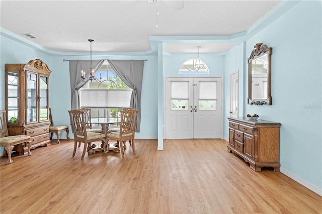 dining space featuring a chandelier, a textured ceiling, and light wood-type flooring