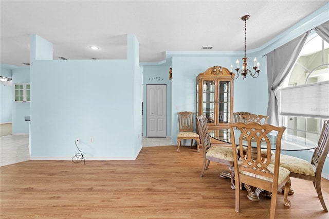 dining room with light hardwood / wood-style floors, crown molding, and a chandelier