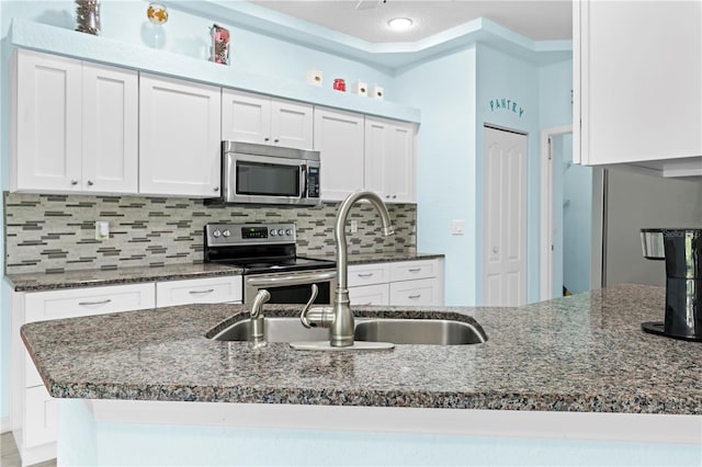 kitchen with backsplash, dark stone countertops, sink, white cabinets, and appliances with stainless steel finishes