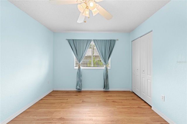 unfurnished bedroom with light hardwood / wood-style flooring, a textured ceiling, a closet, and ceiling fan