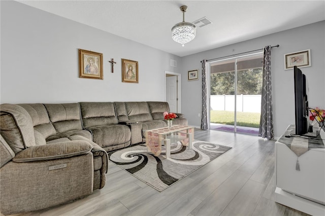 living room with light hardwood / wood-style floors and a notable chandelier