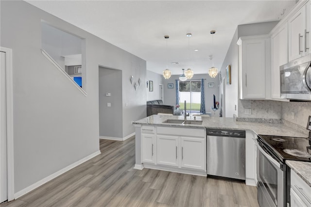 kitchen featuring pendant lighting, white cabinets, sink, kitchen peninsula, and stainless steel appliances