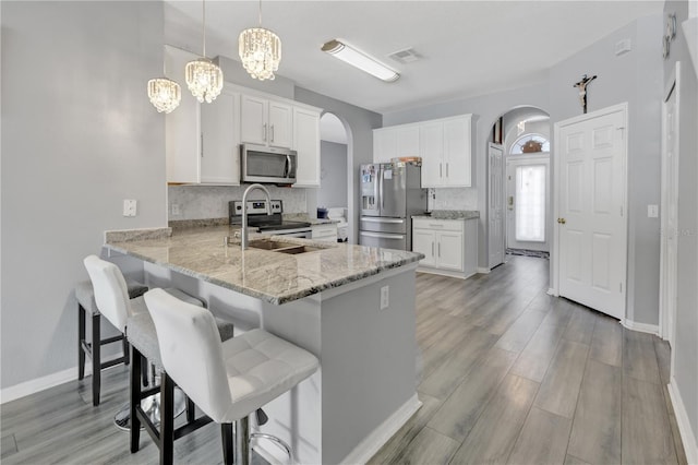 kitchen with tasteful backsplash, white cabinetry, hanging light fixtures, and appliances with stainless steel finishes