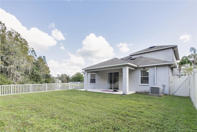 rear view of property featuring cooling unit, a yard, and a patio