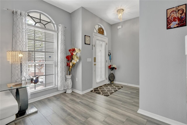 entrance foyer featuring light wood-type flooring, an inviting chandelier, and plenty of natural light