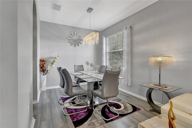 dining area with wood-type flooring and an inviting chandelier