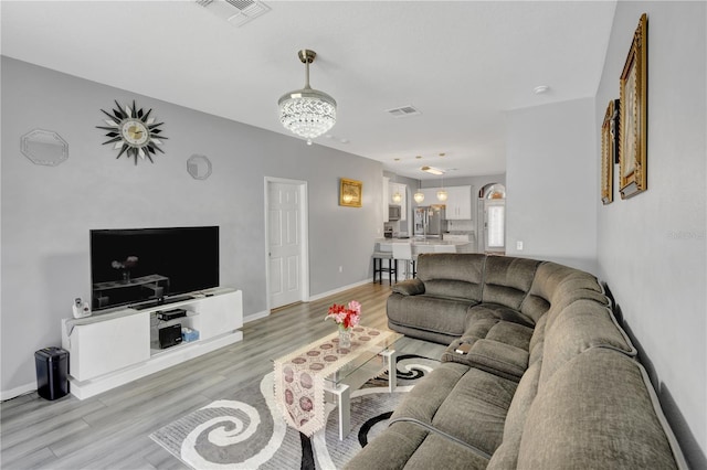 living room with an inviting chandelier and light hardwood / wood-style flooring