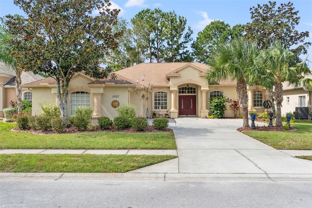 mediterranean / spanish home with a front yard and central air condition unit