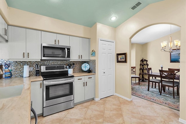 kitchen featuring white cabinetry, stainless steel appliances, tasteful backsplash, and vaulted ceiling