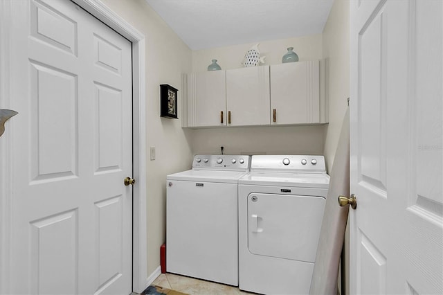 clothes washing area featuring light tile patterned floors, cabinets, and washer and clothes dryer