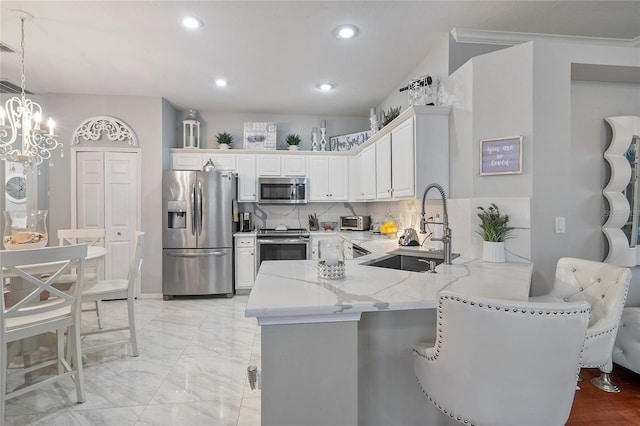 kitchen featuring white cabinetry, sink, backsplash, kitchen peninsula, and appliances with stainless steel finishes