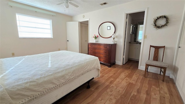 bedroom with ceiling fan, a closet, light hardwood / wood-style floors, ensuite bathroom, and a textured ceiling