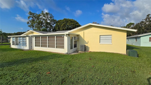 back of property featuring central AC, a sunroom, and a lawn