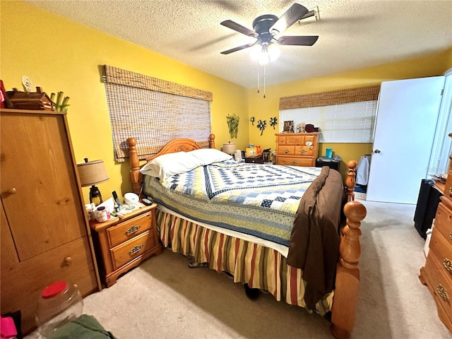 bedroom with ceiling fan, carpet flooring, and a textured ceiling