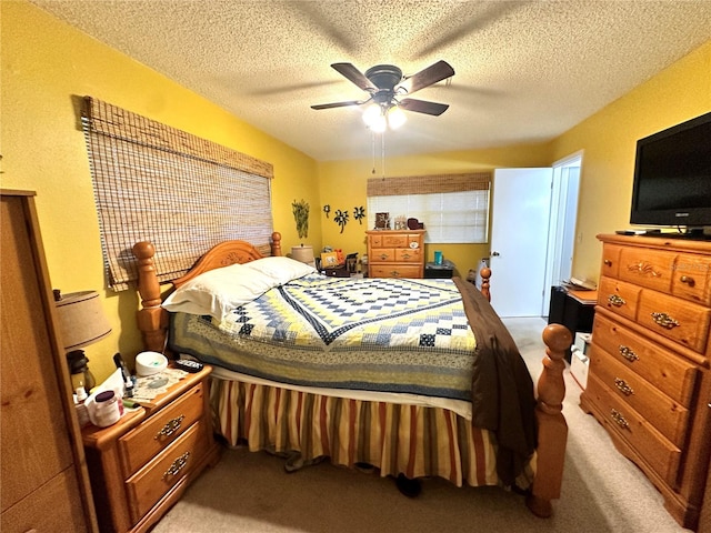 carpeted bedroom featuring ceiling fan and a textured ceiling