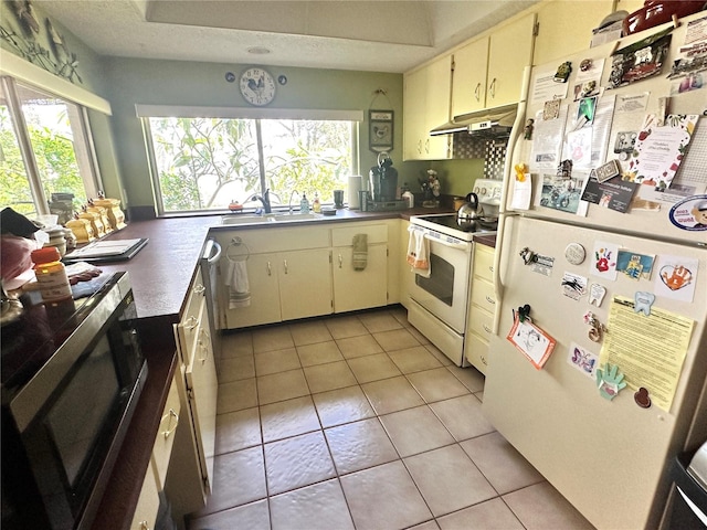 kitchen with a textured ceiling, sink, light tile patterned floors, and white appliances