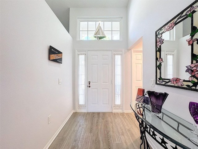 foyer entrance featuring a towering ceiling and light wood-type flooring