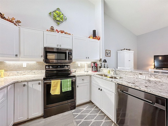 kitchen featuring white cabinetry, light hardwood / wood-style floors, appliances with stainless steel finishes, and vaulted ceiling